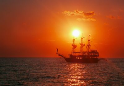 Silhouette of boat in sea during sunset