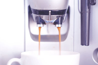 Close-up of coffee pouring in cup from machine