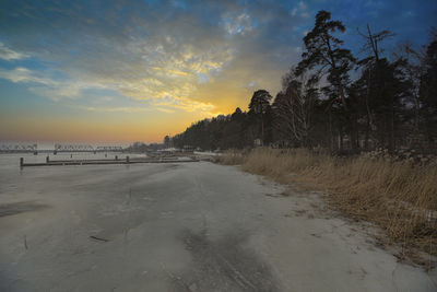 Scenic view of riverside  against sky during sunset in winter haze 