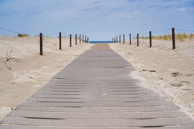 Wooden pier on beach against sky