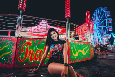 Portrait of woman with illuminated ferris wheel at night