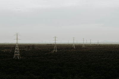 Electricity pylon on field against sky