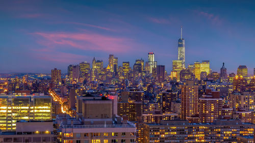 Illuminated cityscape against sky at sunset