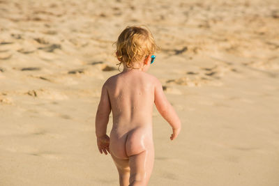 Rear view of shirtless boy on beach