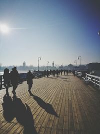 People walking on bridge in city during sunny day