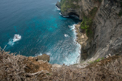 Cliff with waves crashing against a rocky shore, nusa penida, indonesia.