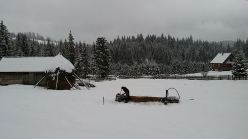 People on snow field against sky during winter