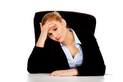 Woman looking away while sitting against white background