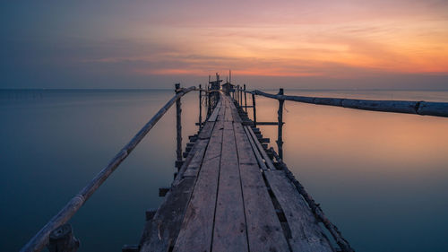 Pier over sea against sky during sunset