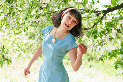Smiling young woman standing against trees