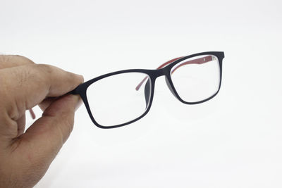 Close-up of hand holding eyeglasses against white background