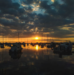 Boats moored at harbor during sunset