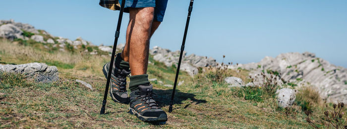 Low section of man wearing shoes on land against sky