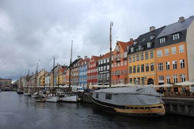 View of boats in river against cloudy sky