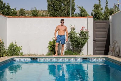 Full length of shirtless man in swimming pool against trees