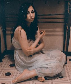 Sad young woman sitting on floor at home