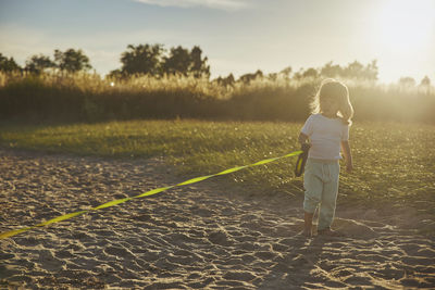 Charming child walking the dog on the beach at sunset