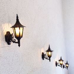 Illuminated lamp on table against wall