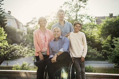 Portrait of happy disabled man with family at yard