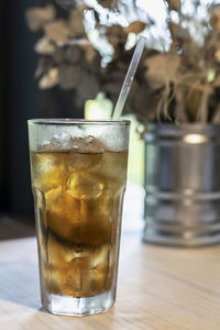 Refreshing cocktail with a straw on the table by the window in the cafe.