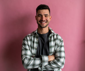 Portrait of young man standing against yellow background