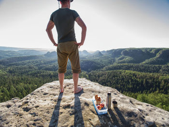 Resting mountaineer stay without shoes on view point. tourist brink metal flask and healthy meal.