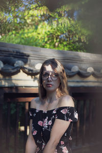 Portrait of beautiful young woman standing by wall outdoors