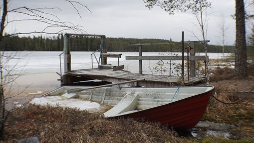 Boat moored on lakeshore against sky