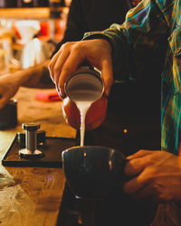 Midsection of barista preparing coffee in cafe