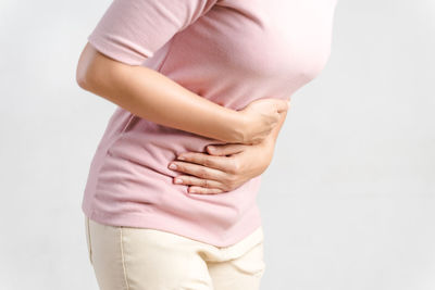 Midsection of woman standing against white background