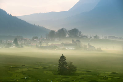 Scenic view of golf court in mountains in foggy weather