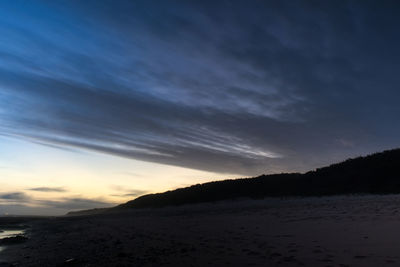 Scenic view of beach against sky at sunset