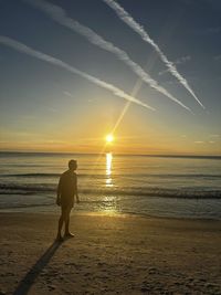 Silhouette man standing by sea against sky during sunset