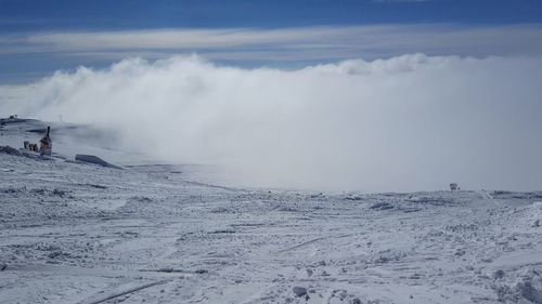 Scenic view of snow covered mountains against cloudy sky