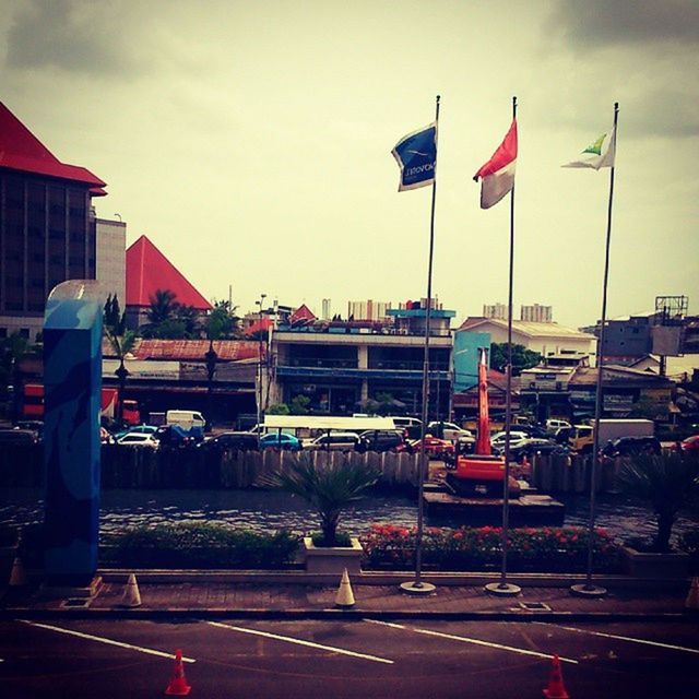 flag, patriotism, building exterior, built structure, architecture, sky, national flag, identity, american flag, transportation, city, mode of transport, street, road, incidental people, day, outdoors, cloud, cloud - sky, car