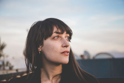 Close-up of thoughtful woman against sky