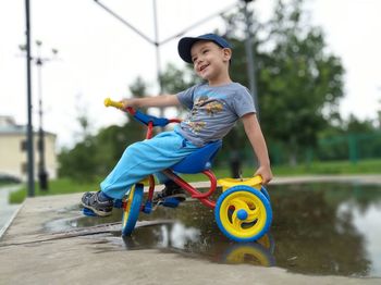 Side view of boy riding bicycle on wet puddle