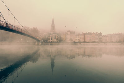 Bridge over river with buildings in misty background