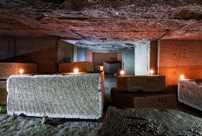 Illuminated candles on rock at archaeological site