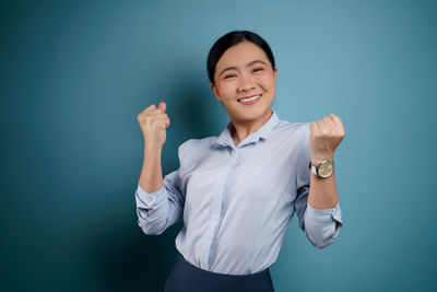 Portrait of smiling young woman against blue background