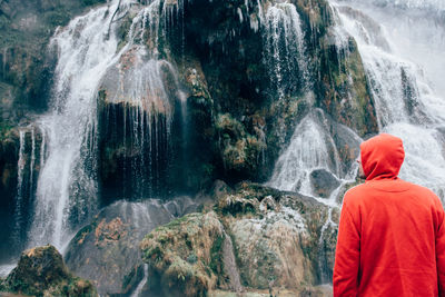 Rear view of man looking at waterfall