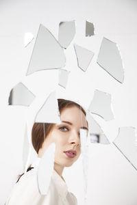 Young woman behind broken mirror