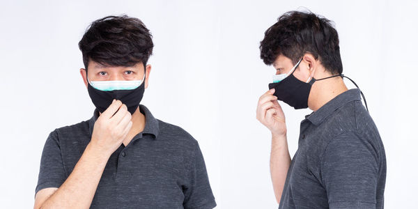 Portrait of young man standing against white background