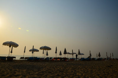 Parasols on beach against clear sky during sunset