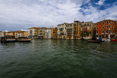 Buildings by grand canal against cloudy sky