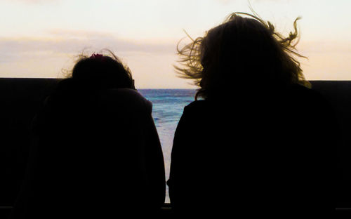 Rear view of silhouette people on beach against sky