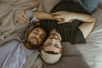 High angle view of gay couple sleeping on bed at home