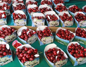 High angle view of fresh red cherries in cardboard boxes at market stall