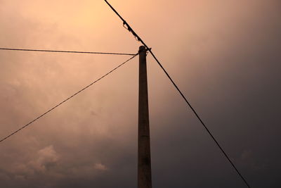 Low angle view of silhouette electricity pylon against sky during sunset