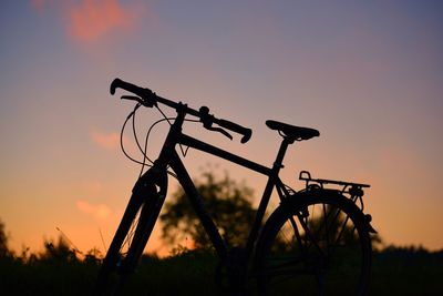 Silhouette of bicycle against orange sky